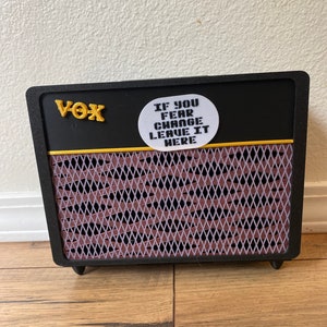 May include: A black Vox guitar amplifier with a white sticker that reads "If you fear change leave it here".