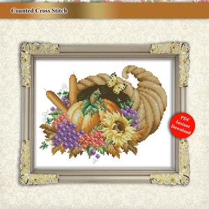 May include: Counted cross stitch pattern featuring a cornucopia overflowing with autumn harvest items, including pumpkins, grapes, sunflowers, and leaves. The pattern is framed in a gold-coloured frame.