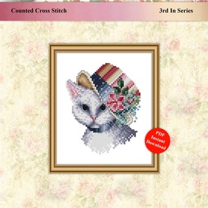 Puede incluir: Patrón de punto de cruz contado con un gato blanco que lleva un sombrero colorido con flores. El patrón se titula "Samantha" y es el 3º de una serie. Descarga instantánea en PDF.