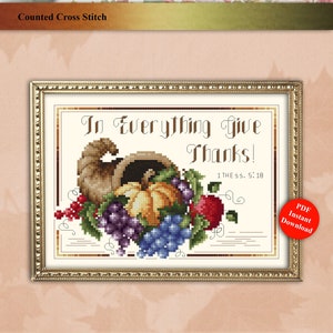 May include: Counted cross stitch pattern featuring a cornucopia overflowing with grapes, pumpkins, and apples. The text "In Everything Give Thanks! 1 Thessalonians 5:18" is stitched in the background.