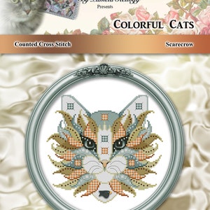 Op de afbeelding: Een geteld kruissteekpatroon met een kleurrijke kat met een patchwork-ontwerp. Het patroon is getiteld "Kleurrijke Katten" en wordt gepresenteerd door Kitty Me Designs by Pamela Kellogg. De kat is ingelijst in een zilveren ovale lijst.