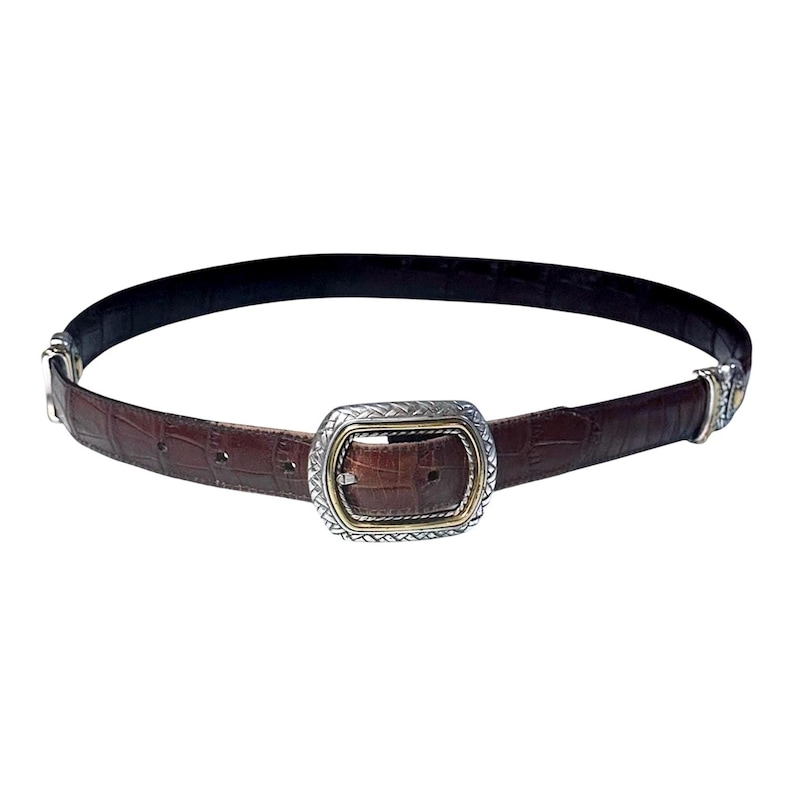May include: A dark brown belt with a textured crocodile-embossed pattern. The belt features a rectangular buckle with a silver-toned braided metal border and a gold-toned inner frame, complemented by matching silver-toned metal hardware at the ends.