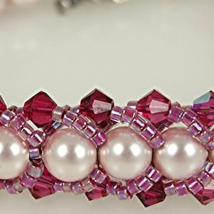 May include: A pink and red beaded bracelet with a woven design. The bracelet is made with small pink and red beads and larger white pearls.