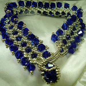 May include: A blue and silver beaded bracelet with a dangling charm. The bracelet is made with small, faceted blue beads and silver beads. The charm is a cluster of blue beads.