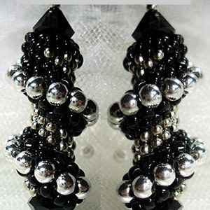 May include: A pair of black and silver beaded earrings with a black crystal at the bottom. The earrings are called "Twister Earrings" by Sue Charette-Hood.