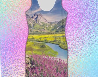 May include: Sleeveless dress featuring a scenic landscape print. The design showcases a mountain range, a river, and fields of yellow and purple flowers. The dress has a scoop neckline and a fitted silhouette.