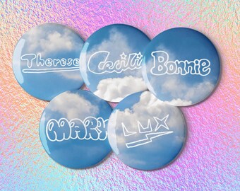 May include: Five round buttons with a sky and cloud design. Each button has a different name in white script: Therese, Cecili, Bonnie, Mary, and Lux. The buttons are on a holographic background.