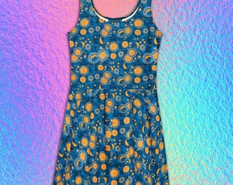 May include: A sleeveless skater dress in a deep blue hue featuring an all-over print of golden yellow suns, crescent moons, and small stars. The garment has a scoop neckline and a flared skirt that falls from the waist in a simple silhouette.