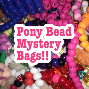 Könnte beinhalten: Nahaufnahme einer Vielzahl von bunten Ponyperlen in einem Haufen. Die Perlen sind in einem zufälligen Muster angeordnet und umfassen Farben wie Rosa, Blau, Rot, Weiß, Orange und Gelb. Der Text "Pony Bead Mystery Bags!!" ist über das Bild gelegt.