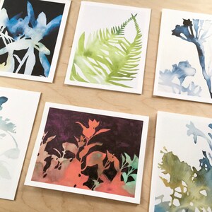 K&ouml;nnte beinhalten: Sechs Aquarellbilder auf wei&szlig;em Karton mit verschiedenen botanischen Silhouetten. Die Bilder sind in Blaut&ouml;nen, Gr&uuml;nt&ouml;nen und Orange gehalten.