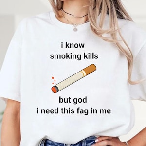 May include: White t-shirt with the text "i know smoking kills but god i need this fag in me" and a cartoon cigarette graphic. The cigarette is beige with a brown filter and a lit orange end.