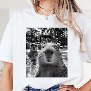 A person wearing a white t-shirt with a black and white photograph of two beavers in a pool.