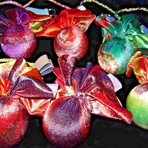 May include: Six colourful fabric pouches with drawstring closures. The pouches are made of a shiny, iridescent fabric with a variety of patterns and colours, including red, green, purple, and gold.