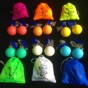 May include: Set of 10 colourful juggling balls with matching drawstring bags. Each ball is attached to a chain and comes in a variety of colours, including red, blue, green, yellow, and white. The bags are made of a soft, lightweight fabric and feature a dragon design with the website address "www.rainbowdragonprops.com".