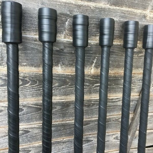 May include: Six black wooden dowels with a spiral pattern wrapped in black tape. The dowels are all the same length and are arranged in a row.