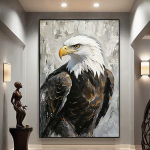 May include: Large framed painting of a bald eagle. The eagle is depicted in a close-up view, with a white head and neck, a yellow beak, and dark brown and white feathers. The background is a textured, abstract gray and white.
