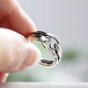 May include: A silver ring with a unique, abstract design. The ring is made of two intertwined bands, creating a delicate and intricate pattern.