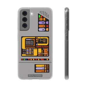 以下が含まれることがあります： スター・トレックをモチーフにしたグレーの携帯電話ケース。ケースには、「SENSOR PLAYBACK」という文字が書かれた黄色と黒の制御パネルと、「9908」、「V7」、「SIM」という文字が書かれたグレーとパープルのディスプレイがあります。