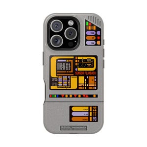 Puede incluir: Funda de teléfono gris con un diseño inspirado en la interfaz LCARS de Star Trek. Presenta detalles en naranja, amarillo y morado, con texto que incluye "SENSOR PLAYBACK" y otros datos técnicos. La funda tiene un recorte para la cámara.