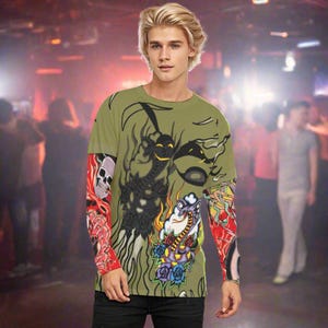 May include: A green long-sleeved shirt with a colorful graphic print of a skull, flowers, and a snake. The shirt has a crew neck and long sleeves with a tattoo-like design.