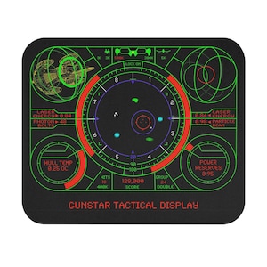 May include: Black mousepad featuring a retro-futuristic tactical display design with green and red accents. The display includes readouts for laser energy, hull temperature, and power reserves, with the text "GUNSTAR TACTICAL DISPLAY".