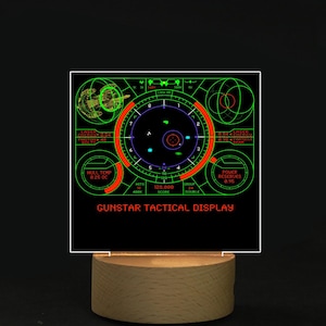 May include: A retro-style Gunstar Tactical Display night light. The display features a green and red graphic with text, set on a wooden base. The display shows a targeting system with various readouts.