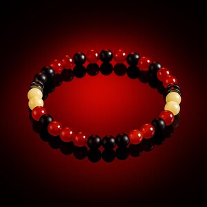 Peut inclure: Un bracelet de perles rondes rouges, noires et crème. Le bracelet est disposé en cercle sur un fond rouge. Les perles ont une surface lisse et réfléchissante, créant un contraste saisissant.