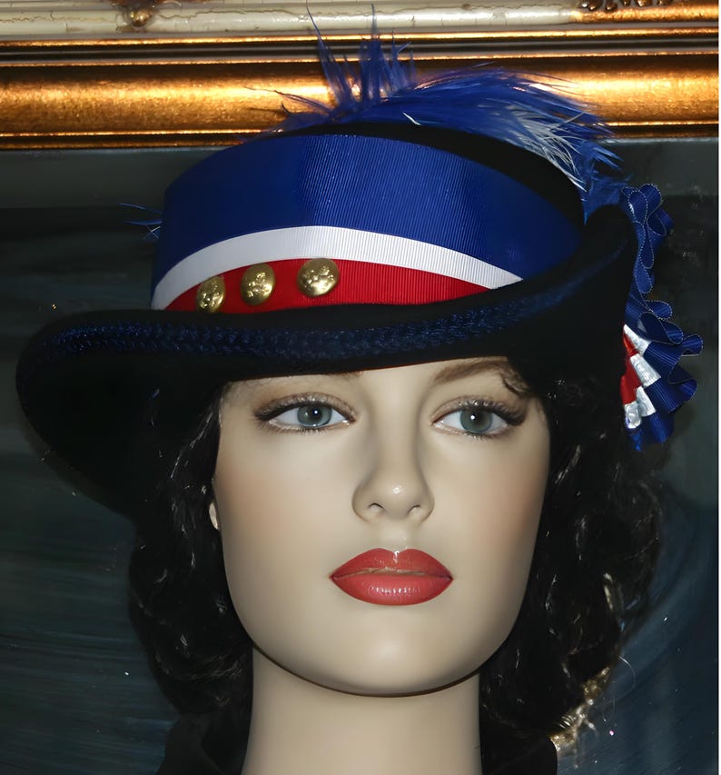 May include: A black hat with a wide brim, decorated with a blue and white striped ribbon, red ribbon, and gold buttons. The hat has a blue feather and a decorative ribbon on the side. The hat is worn by a mannequin head.