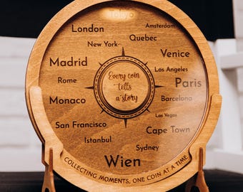 May include: A circular wooden coin holder, engraved with city names and the phrase "Every coin tells a story." The holder also features the text "Collecting moments, one coin at a time." The design is supported by wooden stands.