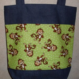 May include: A blue denim tote bag with a green fabric lining featuring a repeating pattern of monkeys covering their mouths and laughing. The fabric has white polka dots.