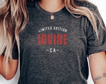 May include: A dark grey t-shirt with a white circle around the text "LIMITED EDITION IRVINE -CA-" in red lettering.