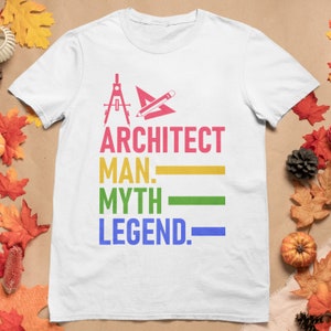 Puede incluir: Camiseta blanca con un diseño gráfico colorido. El gráfico presenta una brújula, una regla y un lápiz con el texto "ARCHITECT MAN. MYTH LEGEND."