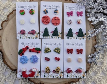 May include: Six cards with Christmas themed polymer clay earrings. The cards are white with red and green text that reads "Mimsy Maple You look gorgeous". The earrings include Christmas trees, ornaments, bows, stockings, and cars.