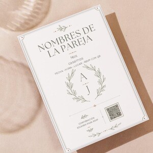 Puede incluir: Una tarjeta de invitación de boda rectangular blanca con el texto NOMBRES DE LA PAREJA, Nos casamos, FECHA HORA LUGAR RSVP CON QR, CONFIRMACION, una corona de laurel central rodeando las letras A y J, y un código QR incluido.