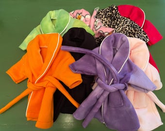 Puede incluir: Una colección de batas de baño pequeñas de forro polar suave en varios colores, incluyendo naranja, morado, negro, verde claro, rosa y un estampado de leopardo. Cada bata cuenta con cuello tipo chal, mangas largas y un cinturón a juego.
