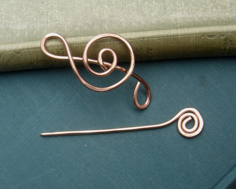 May include: A copper wire treble clef and a copper wire spiral pin. The pin is straight with a spiral on one end.