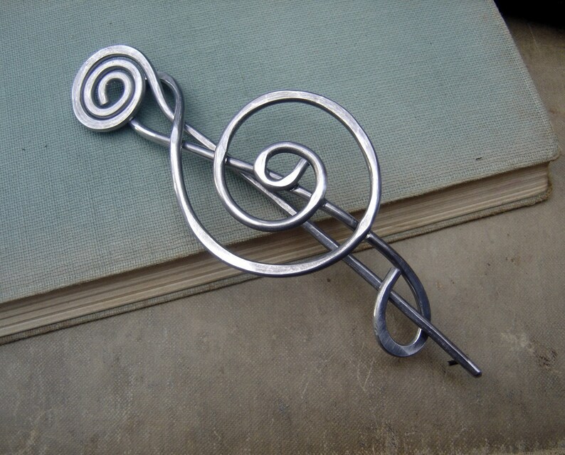 May include: Silver metal treble clef hair clip. The treble clef is a musical symbol.