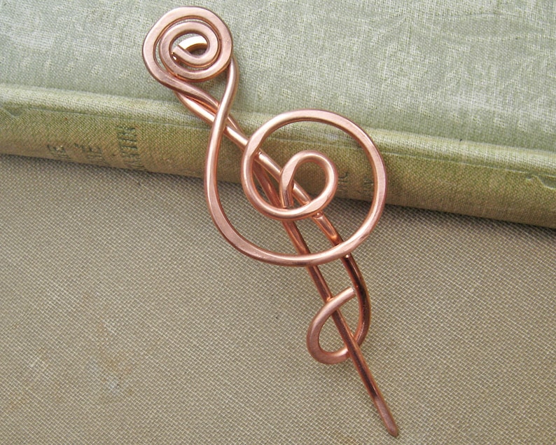 May include: A copper wire hair pin shaped like a treble clef.