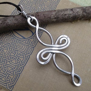 May include: A silver metal pendant with a unique, abstract design. The pendant is made of wire that is twisted and looped into a complex pattern.
