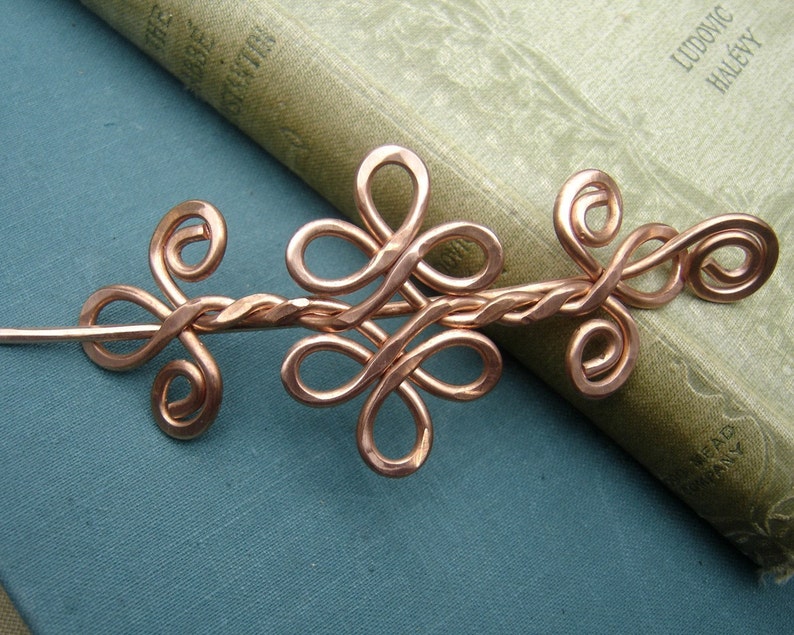 May include: A copper wire hair stick with a twisted wire design and a decorative floral pattern. The stick is about 6 inches long.