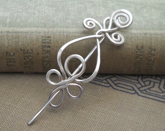 May include: Silver hair stick with a decorative swirl design. The stick is made of wire and has a smooth, polished finish.