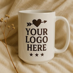 Puede incluir: Taza de cerámica blanca con un diseño de corazón y flecha negro. El texto "YOUR LOGO HERE" está impreso en la taza.