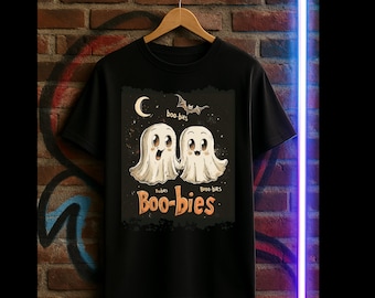 May include: Black t-shirt featuring a Halloween-themed graphic. The design includes two cartoon ghosts with the text "Boo-bies" below them. A crescent moon and a bat are also part of the design.
