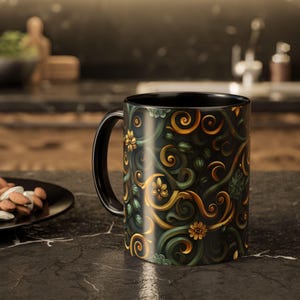 Puede incluir: Taza de cerámica negra con un diseño floral en dorado, verde y amarillo. La taza tiene un asa y un interior negros, y el patrón floral cubre toda la superficie. La taza está sobre una encimera oscura.