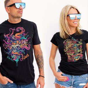 May include: Two people wearing black t-shirts with a colorful, abstract design and the text "Experience the Chaos." Both are wearing large, reflective sunglasses. The background is plain white.