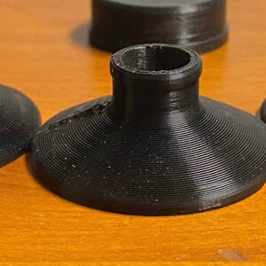 May include: Three black plastic bases with a raised center hole. The bases are designed to be used as a stand for a variety of objects.