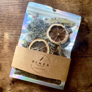 Peut inclure: Un sac en plastique transparent rempli de lavande séchée, de feuilles de laurier et de tranches de citron. Le sac porte une étiquette brune sur laquelle est inscrit "Pine & Pestle - House of Herbals."