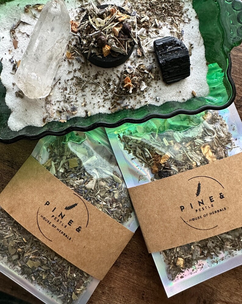 Pode incluir: Duas bolsas de pl&aacute;stico transparentes cheias de ervas e flores secas. As bolsas t&ecirc;m etiquetas de papel castanho com o texto "Pine & Pestle, House of Herbals".