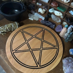 May include: A wooden pentagram altar plate with a black outline. The plate is round and has a natural wood finish.