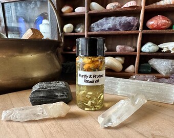 May include: A small glass bottle filled with a yellow liquid and dried herbs. The bottle has a black cap and a white label that reads "Purify & Protect Ritual Oil".